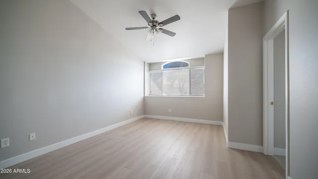 an empty room with wooden floor chandelier fan and windows