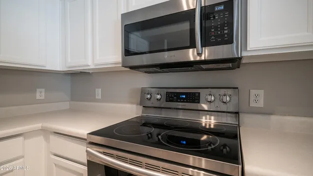 a kitchen with stainless steel appliances granite countertop white cabinets and a stove top oven