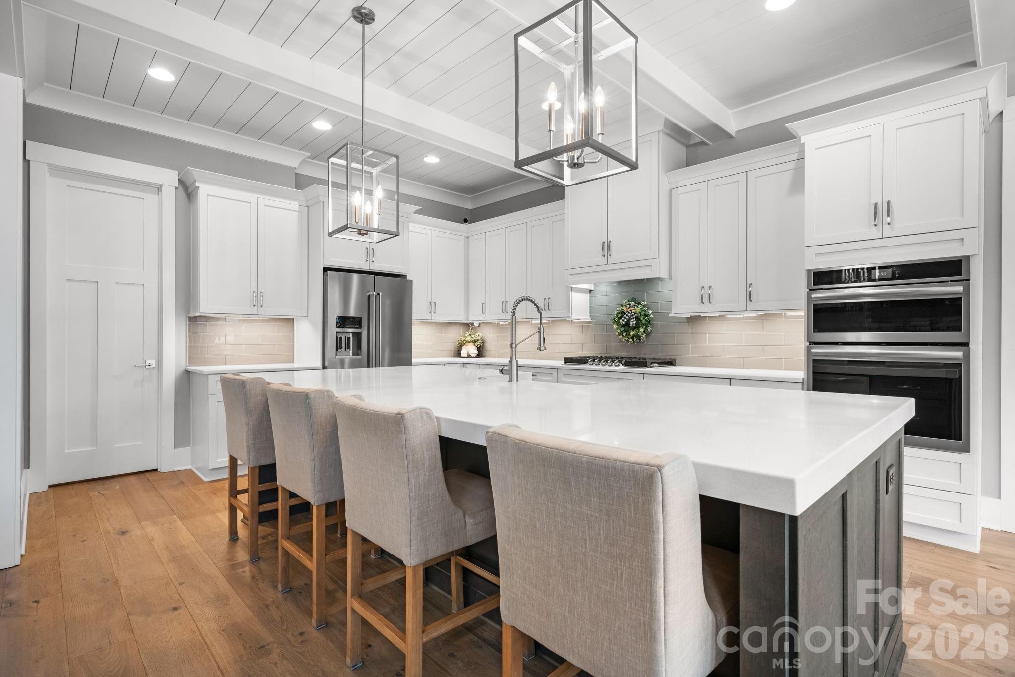 7269 Savannah Denver, NC 28037 - Photo 5 of 48 a kitchen with stainless steel appliances kitchen island granite countertop a table chairs in it and wooden floors