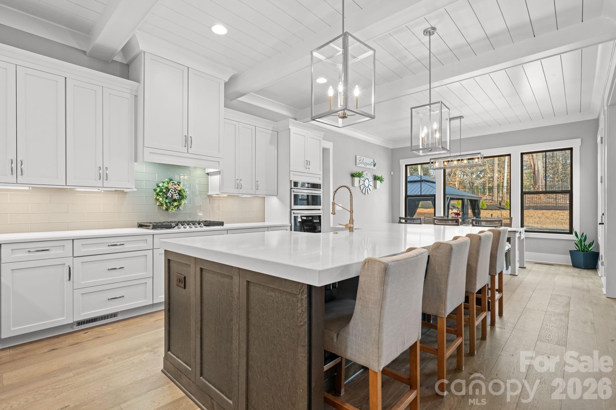 7269 Savannah Denver, NC 28037 - Photo 7 of 48 a kitchen with stainless steel appliances kitchen island granite countertop a table chairs in it and white cabinets