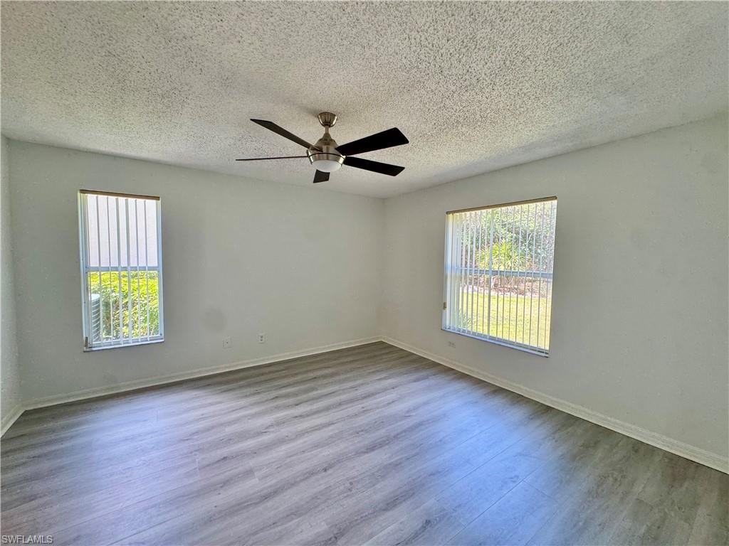 661 Squire Circle, Unit 101 Naples, FL 34104 - Photo 18 of 25 a view of an empty room with a window and wooden floor