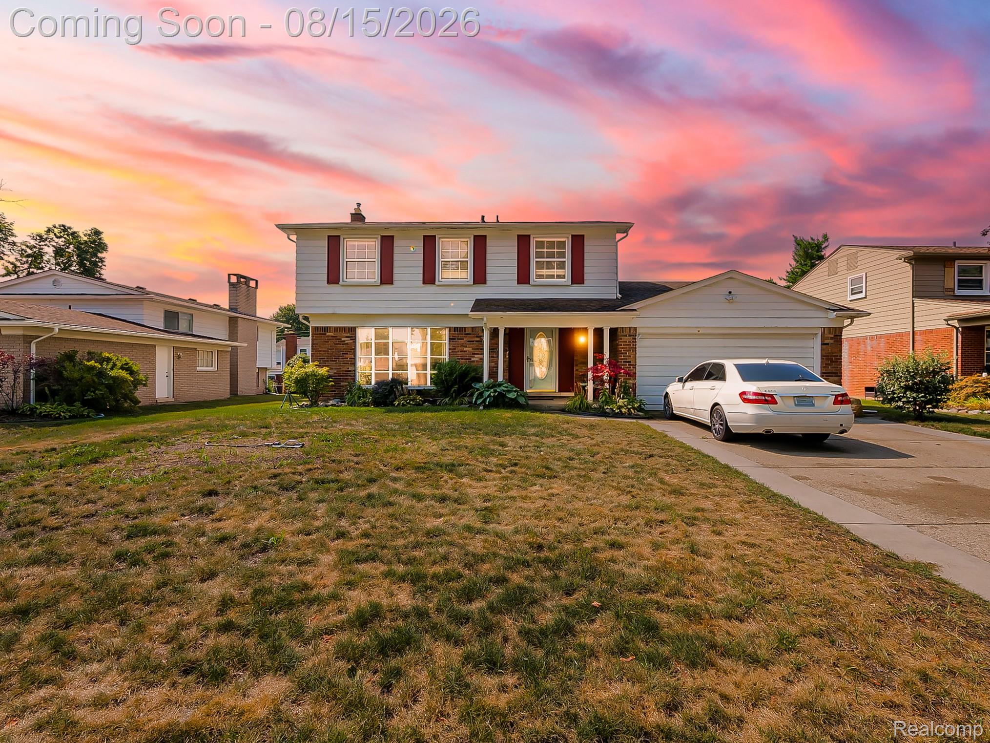 21131 Harvard Road Southfield, MI 48076 - Photo 1 of 33 Two-story colonial home featuring a welcoming front facade with illuminated windows, attached two-car garage, and a spacious front lawn with mature landscaping