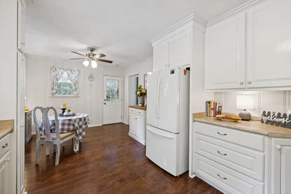 a kitchen with a stove a sink dishwasher a dining table and chairs with wooden floor