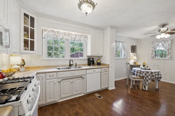 a kitchen with stainless steel appliances a stove a sink a dining table and chairs