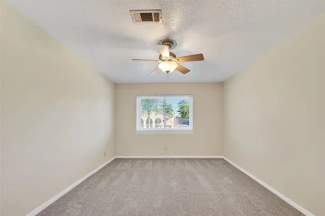 an empty room with a chandelier fan and window