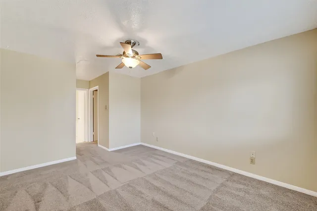 an empty room with a ceiling fan and a window