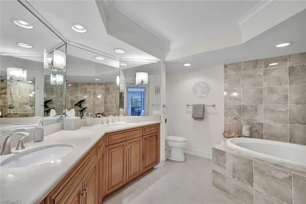 a large bathroom with a double vanity sink a toilet a mirror and shower