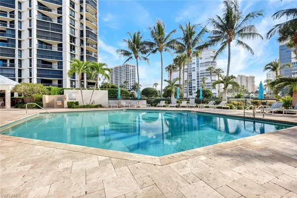 a view of a swimming pool with a lawn chairs and palm trees