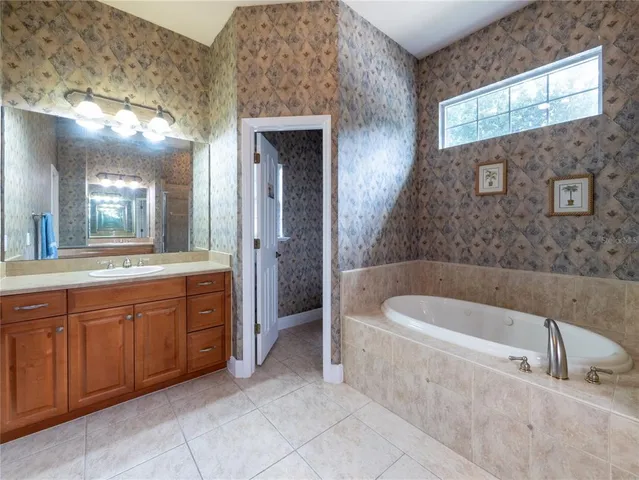 a spacious bathroom with a tub sink and mirror