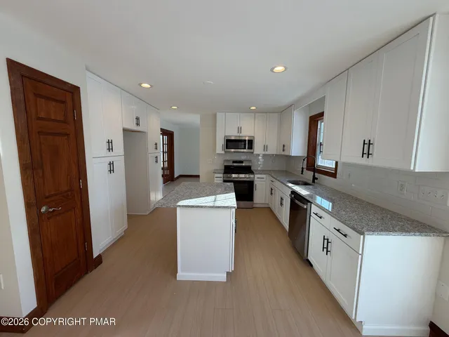 a large kitchen with stainless steel appliances granite countertop a refrigerator a sink a stove a microwave and island