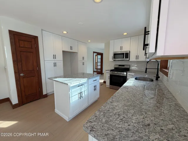 a kitchen with granite countertop a refrigerator oven a sink a stove and cabinets