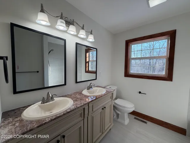 a bathroom with a granite countertop sink mirror and toilet