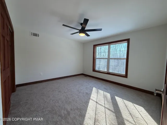 an empty room with windows and fan