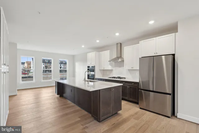 a large kitchen with a center island wooden floor stainless steel appliances and windows