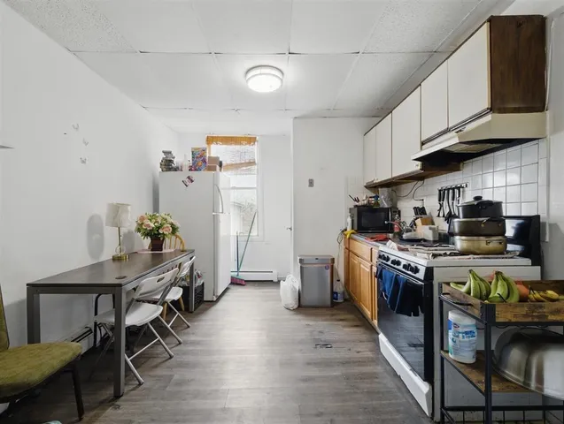 a kitchen with stainless steel appliances granite countertop a stove top oven a sink dishwasher a dining table and chairs with wooden floor