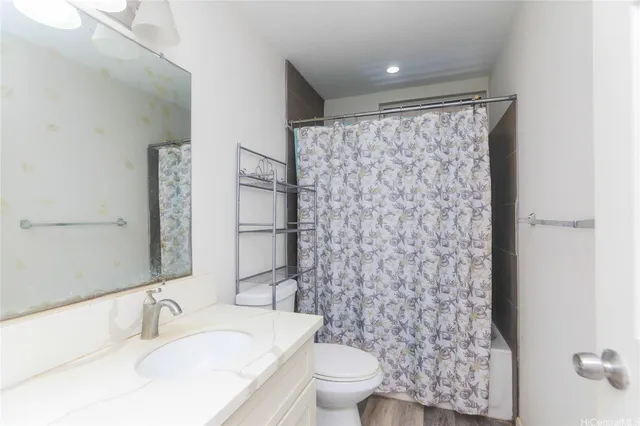 a bathroom with a granite countertop sink a toilet a mirror and shower curtain