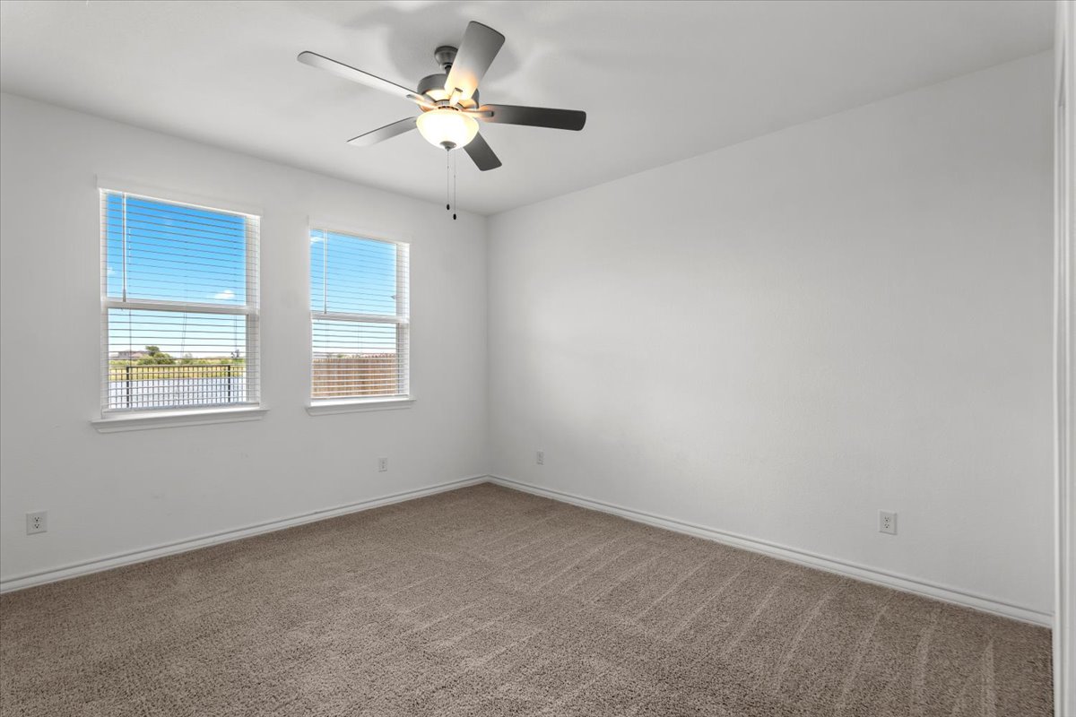500 Stinchcomb Road Hutto, TX 78634 - Photo 31 of 37 A well-lit bedroom features plush carpeting and multiple windows.