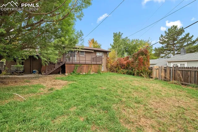 a view of a house with backyard and wooden fence