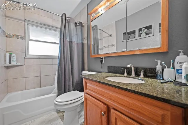 a bathroom with a granite countertop sink mirror vanity and toilet