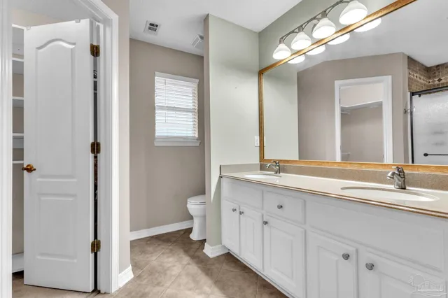 a bathroom with a double vanity sink and mirror with toilet