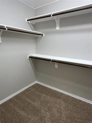 an empty room with a chandelier fan and windows