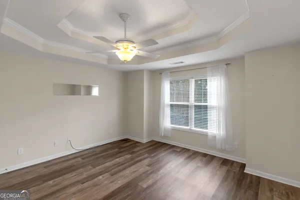 a view of an empty room with a window and wooden floor