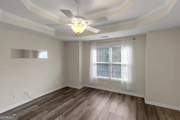 a view of an empty room with wooden floor and a window