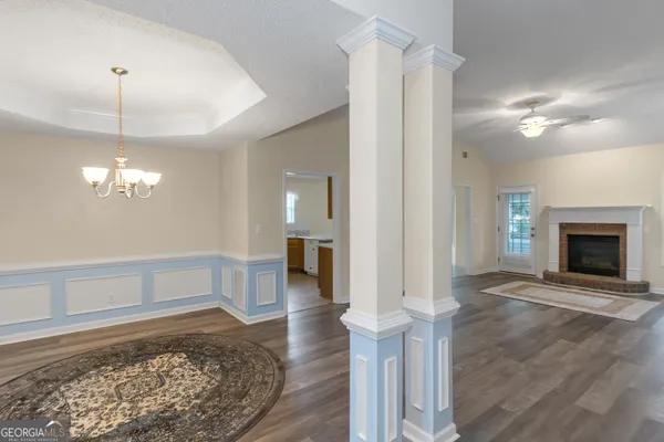 a view of a livingroom with a fireplace a chandelier and wooden floor