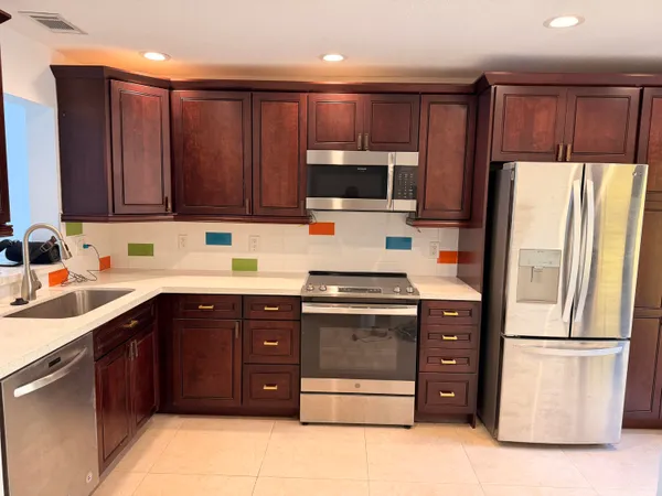 a kitchen with stainless steel appliances granite countertop a refrigerator stove a sink dishwasher and microwave