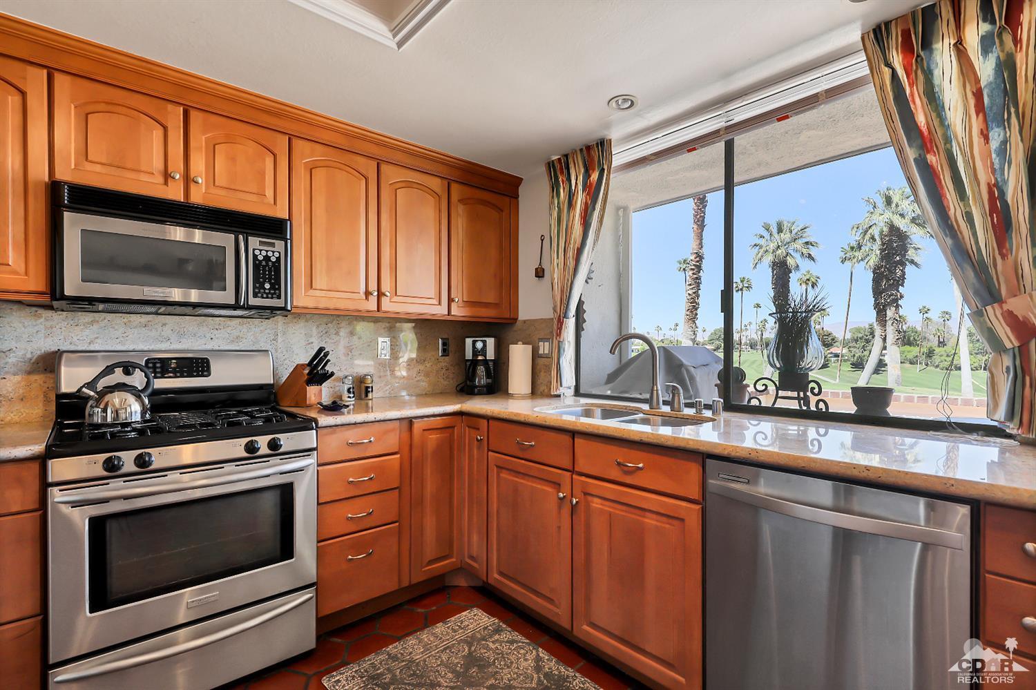6 Palomas Drive Rancho Mirage, CA 92270 - Photo 8 of 20 a kitchen with stainless steel appliances granite countertop a stove microwave and cabinets