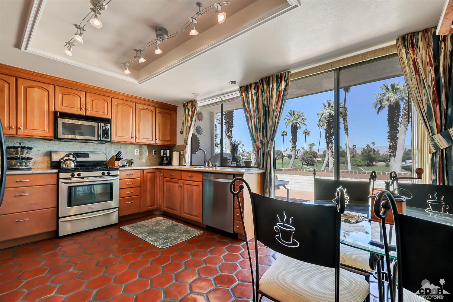 6 Palomas Drive Rancho Mirage, CA 92270 - Photo 9 of 20 a kitchen with stainless steel appliances granite countertop a stove top oven a sink a dining table and chairs with wooden floor