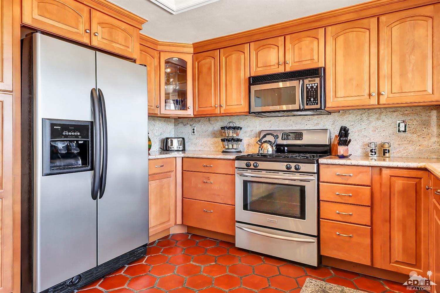 6 Palomas Drive Rancho Mirage, CA 92270 - Photo 10 of 20 a kitchen with stainless steel appliances granite countertop a refrigerator stove and white cabinets with wooden floor