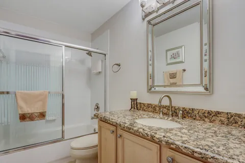 a bathroom with a granite countertop sink toilet and shower