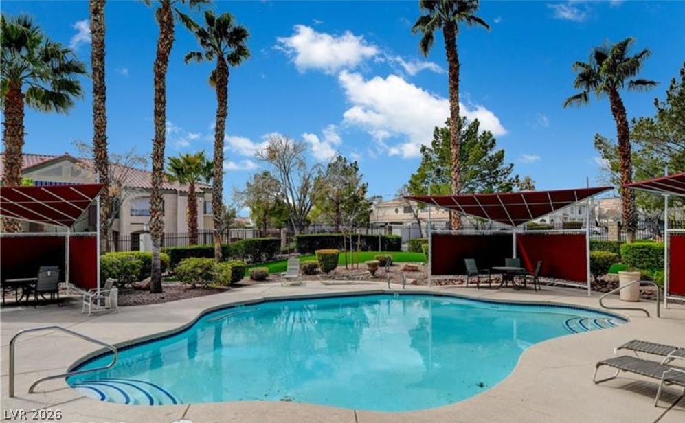 7885 West Flamingo Road, Unit 1008 Las Vegas, NV 89147 - Photo 11 of 29 An inviting pool area, complete with palm trees and shade structures, offers a perfect outdoor retreat.