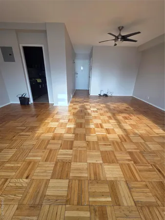 a view of empty room with wooden floor and fan