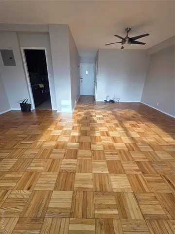 a view of empty room with wooden floor and fan