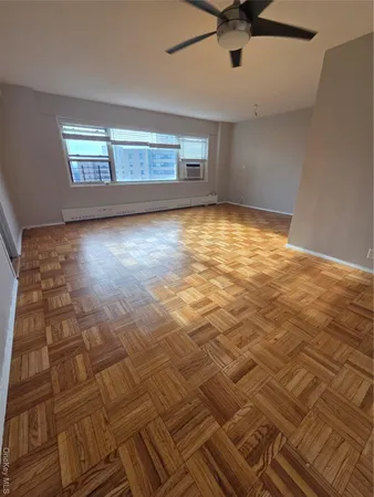 a view of empty room with wooden floor and fan