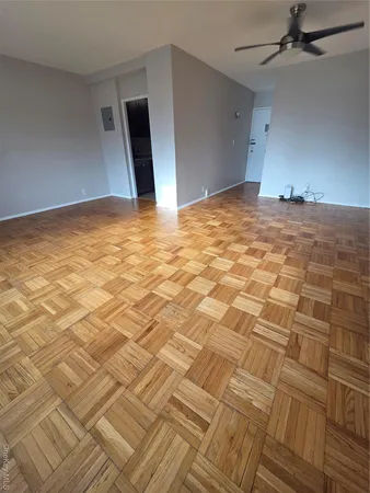 a view of empty room with wooden floor and fan
