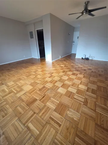 a view of empty room with wooden floor and fan