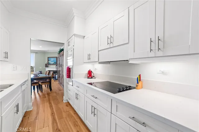 a kitchen that has a lot of white cabinets and wooden floor