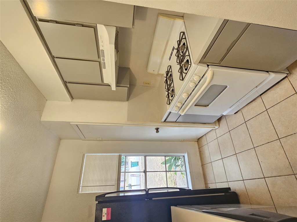 6000 Emerald Forest Drive, Unit A Austin, TX 78745 - Photo 7 of 19 a kitchen with a stove a sink and a refrigerator