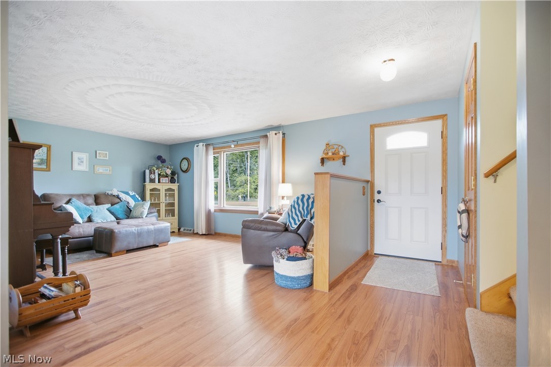5972 Keller Road Akron, OH 44319 - Photo 5 of 29 Wood-finish flooring throughout, light blue wall paint, white trim, white front entry door with transom window, and a built-in wood and grey half-wall partition
