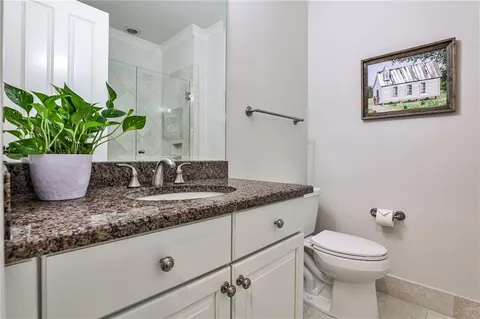 a bathroom with a granite countertop sink a toilet and with mirror