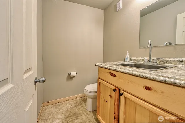 a bathroom with a granite countertop sink a toilet and a mirror