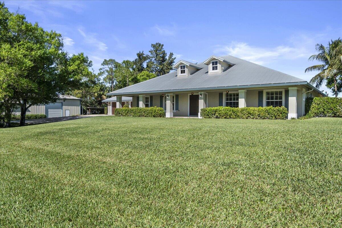 10975 Randolph Siding Road Jupiter, FL 33478 - Photo 9 of 97 a front view of a house with a garden