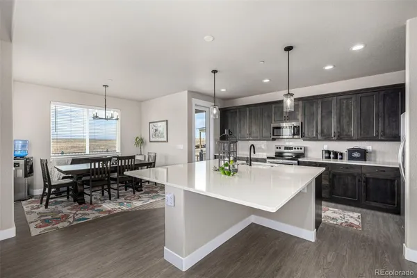 a kitchen with stainless steel appliances granite countertop a stove refrigerator a dining table and chairs with wooden floor