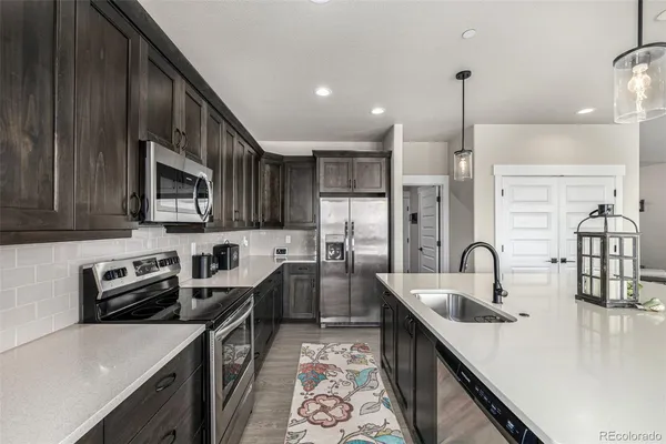 a kitchen with stainless steel appliances a sink a stove a refrigerator a center island and cabinets