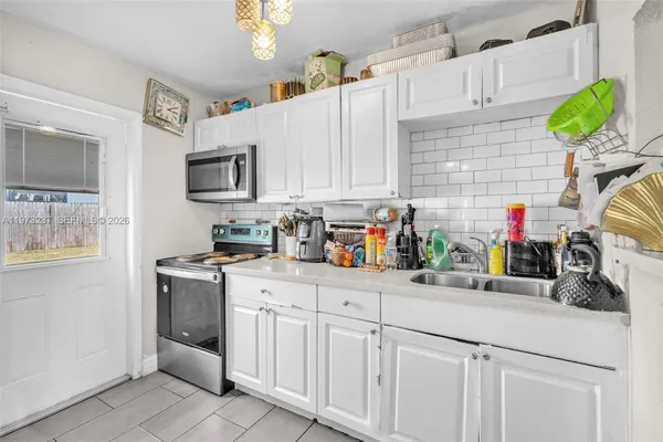 a kitchen with white cabinets and appliances