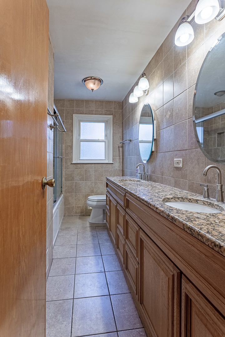 1506 West Palm Drive Mount Prospect, IL 60056 - Photo 9 of 19 a large bathroom with a granite countertop sink a toilet a mirror and vanity