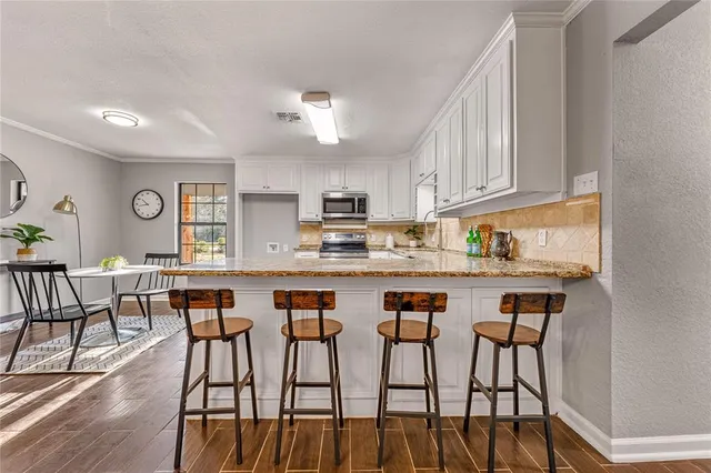 a kitchen with stainless steel appliances granite countertop a dining table chairs and granite counter tops